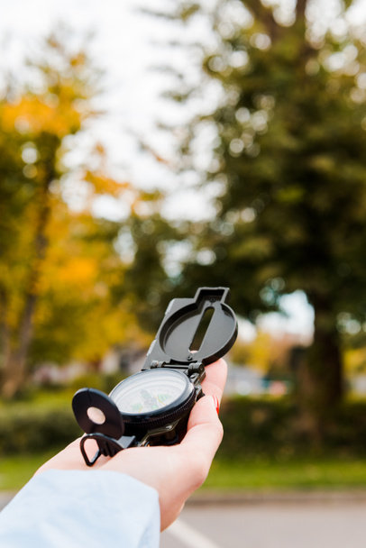 przycięty widok kobiety trzymającej kompas w jesiennym parku  - Zdjęcie, obraz