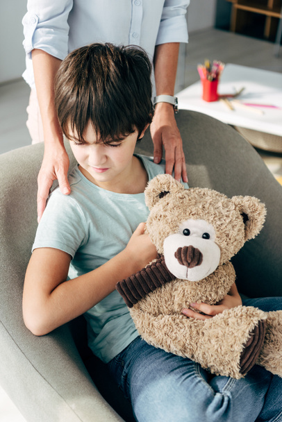 vue recadrée d'enfant psychologue étreignant enfant avec dyslexie tenant ours en peluche
  - Photo, image