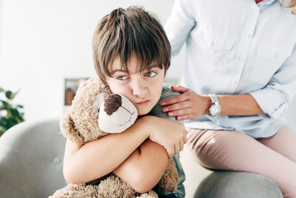 triste niño con dislexia sosteniendo osito de peluche y niño psicólogo abrazándolo
  - Foto, Imagen