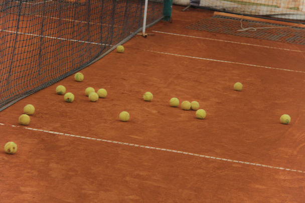 Tennis balls on red court with gray net - Photo, Image