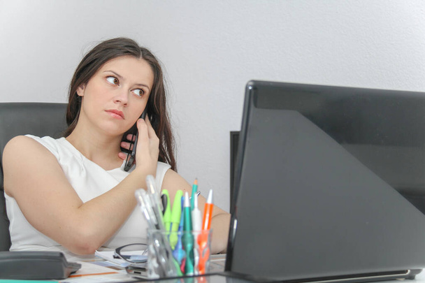 Attrayant femme d'affaires utilisent téléphone intelligent et assis à sa wor
 - Photo, image