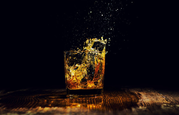 Isolated shot of whiskey with splash on black background - Fotografie, Obrázek