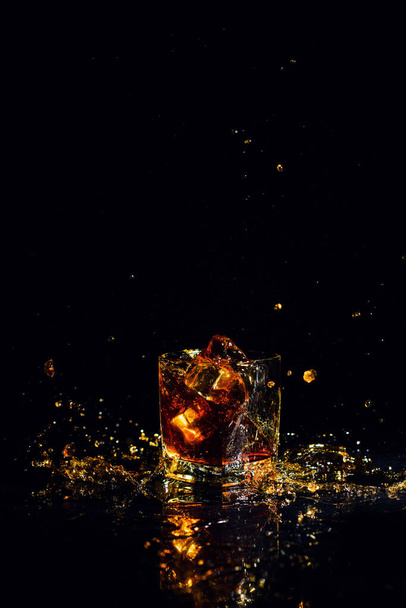 Isolated shot of whiskey with splash on black background - Photo, Image