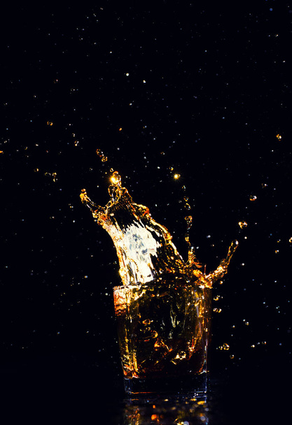 Isolated shot of whiskey with splash on black background - Foto, imagen