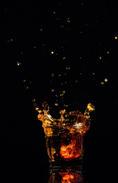 Geïsoleerde shot whisky met splash op zwarte achtergrond - Foto, afbeelding