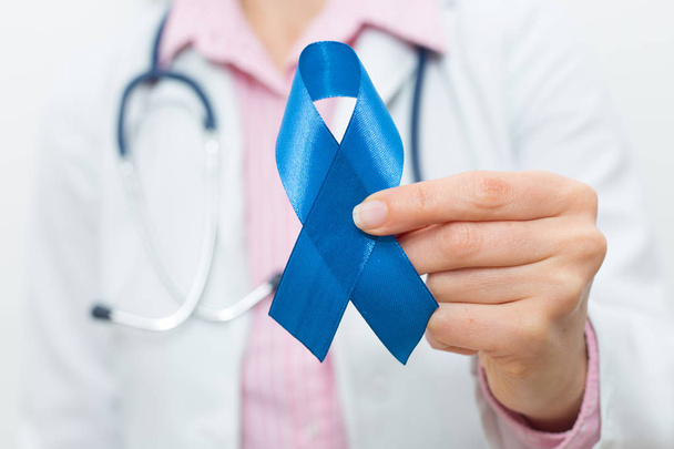 The doctor is holding a blue ribbon in his hand. The concept of prostate cancer. - Fotó, kép