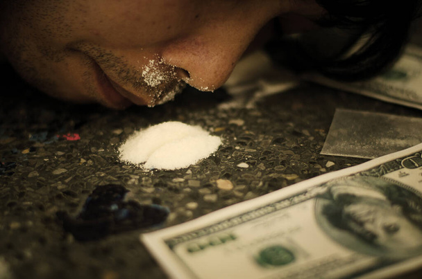fekete-fehér fénykép egy férfiról, aki kokaint szimatol, csövek segítségével dollár formájában. - Fotó, kép
