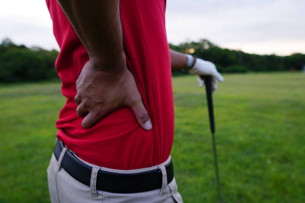 golfer hand holding stick and another hand on the back, back hurts - Foto, Bild