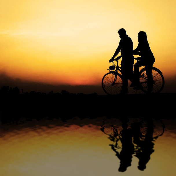 couple riding on a bike along the lake at the sunset - Фото, зображення