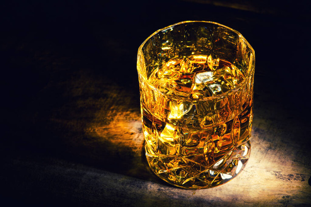 whiskey with ice cubes on wooden background - Foto, afbeelding