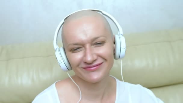 close-up. a bald woman in headphones listens to music and moves her head to the beat of the music. - Video