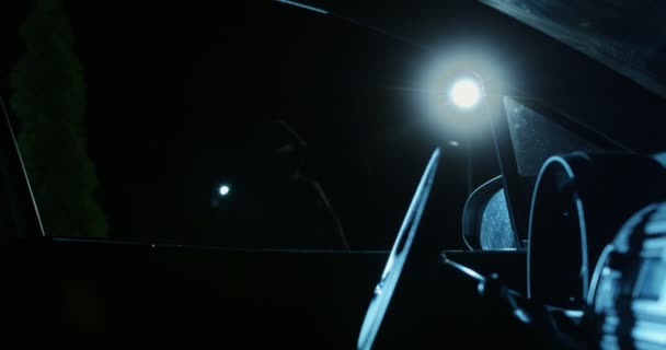 Araba hırsızı, kar maskesi ve el feneri güvenlik kamerasıyla gece vakti içeriye bakan bir araç çalmaya çalışıyor. - Video, Çekim