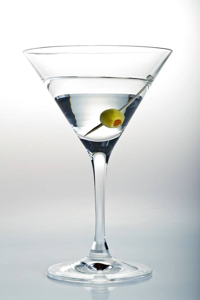 Vertical shot of a glass of Martini and an olive in it on a white background - Фото, изображение