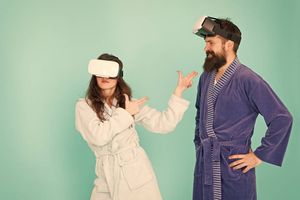 Future is closer than you think. Man and woman explore VR at home. VR technology and future. VR communication. Exciting impressions. Couple in bathrobes wear VR glasses. Gaming and entertainment - Photo, image