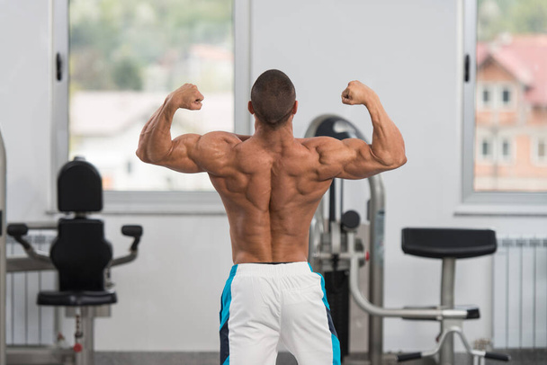 Biceps Pose Of A Young Man In Gym - Φωτογραφία, εικόνα