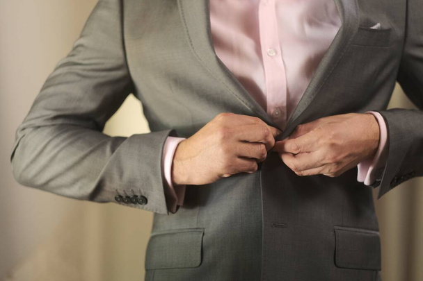 Closeup shot of a person wearing a formal outfit buttoning his suit isolated on a white background - Foto, Imagen