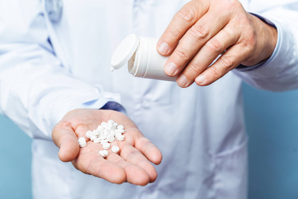 doktor drží lahvičku pilulek na bílém pozadí. Koncept medicíny, farmakologie, zdravotní péče - Fotografie, Obrázek
