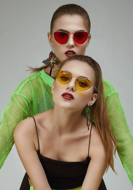 Дві елегантні гламурні дівчата-близнюки в модних неонових зелених сукнях
 - Фото, зображення