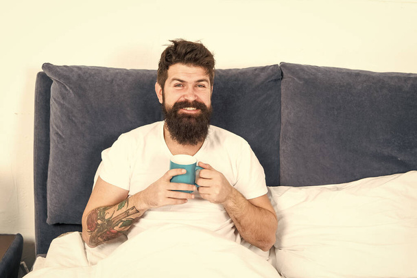 Relax and rest. Humanity runs on coffee. Man brutal handsome hipster relaxing bedroom drink coffee. Bearded guy enjoy morning coffee. Tune in to new day. Morning awakening better with cup coffee - Fotó, kép