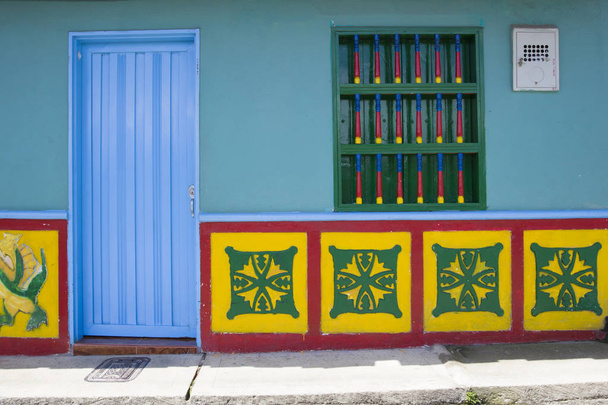 Гватепия, КОЛОМБИЯ - 11 СЕНТЯБРЯ 2019: Деталь из красочного фасада здания в Гватапе, Колумбия. Каждое здание в городе Guatape имеет яркие плитки цвета вдоль нижней части фасада
. - Фото, изображение