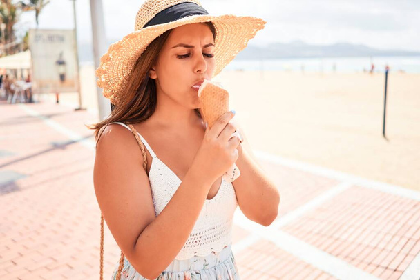 junge schöne Frau isst Eistüte am Strand an einem sonnigen Sommertag im Urlaub - Foto, Bild