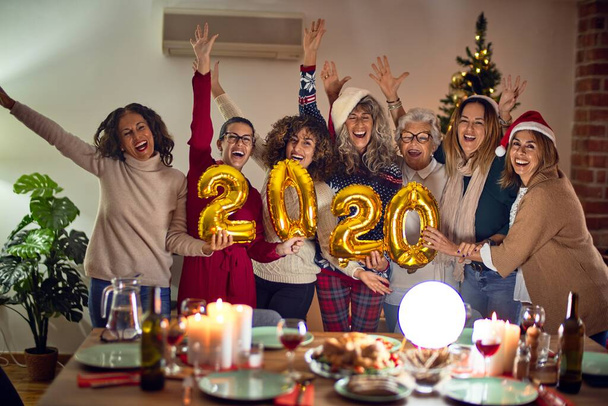 Gyönyörű női csoport mosolyogva boldog és magabiztos. Pózolás körül karácsonyfa gazdaság 2020 ballonok otthon - Fotó, kép
