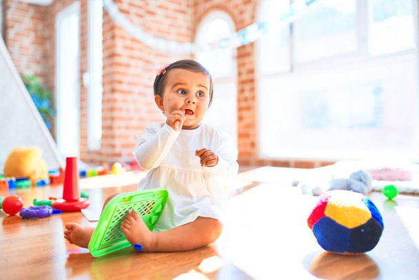 Hermoso bebé feliz en el jardín de infantes alrededor de juguetes coloridos dibujo en pizarra magnética
 - Foto, imagen