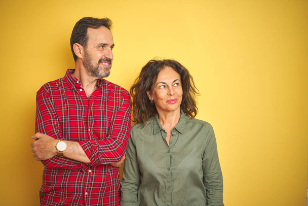 Beautiful middle age couple over isolated yellow background smiling looking to the side and staring away thinking. - Fotografie, Obrázek