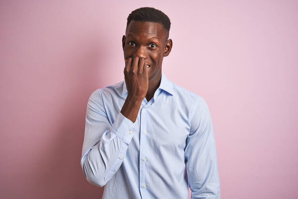 African american man wearing blue elegant shirt standing over isolated pink background looking stressed and nervous with hands on mouth biting nails. Anxiety problem. - Foto, afbeelding