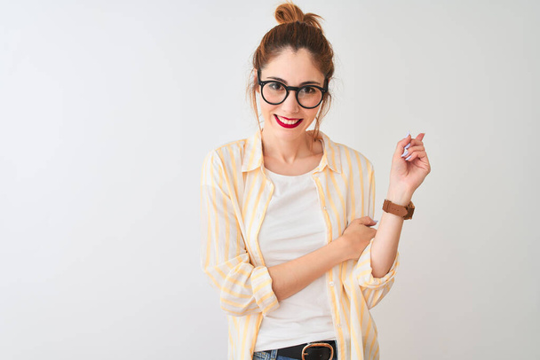 Redhead woman wearing striped shirt and glasses standing over isolated white background with a big smile on face, pointing with hand and finger to the side looking at the camera. - Φωτογραφία, εικόνα