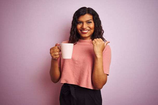 Transsexual transgender woman drinking cup of coffee over isolated pink background pointing and showing with thumb up to the side with happy face smiling - Фото, изображение