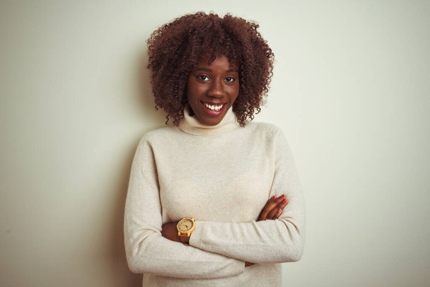 Fiatal afrikai afro nő garbó pulóvert visel elszigetelt fehér háttér boldog arc mosolyogva keresztbe tett karokkal nézi a kamerát. Pozitív személy. - Fotó, kép