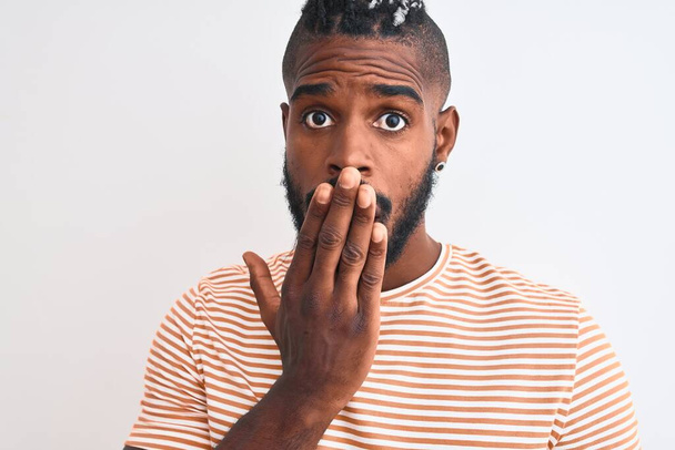 Африканський американець з плечима в смугастій футболці над ізольованим білим фоном рот з ручним шокований від сорому за помилку, вираз страху, злякався в тиші, секретної концепції - Фото, зображення