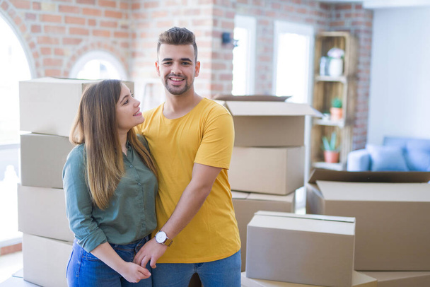 Young beautiful couple in love around cardboard boxes moving to  - Foto, imagen