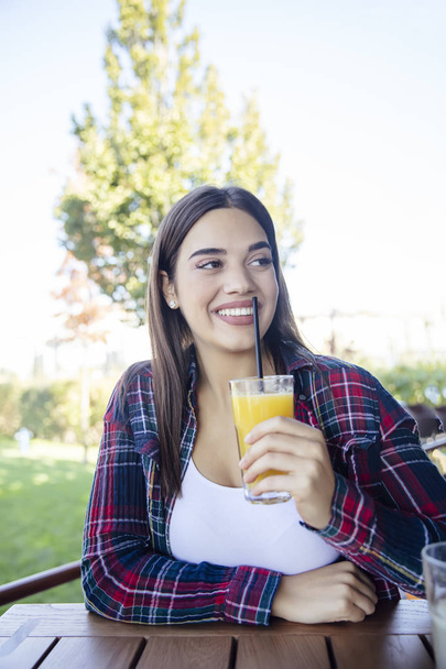 Πορτρέτο της νεαρής ευτυχούς χαμογελαστή γυναίκα πίνοντας χυμό πορτοκάλι εξωτερική - Φωτογραφία, εικόνα