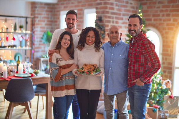 Kaunis perhe hymyilee onnellisena ja itsevarmana. Seisoo ja poseeraa puu juhlii joulua kotona
 - Valokuva, kuva