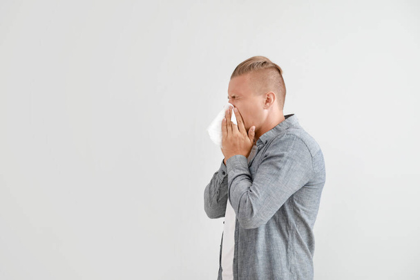 Young man suffering from allergy on light background - Photo, image