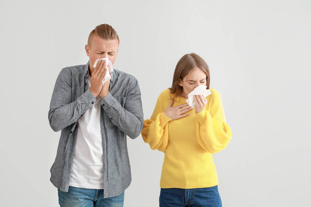 Young couple suffering from allergy on light background - 写真・画像