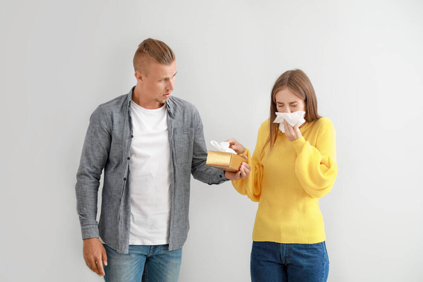 Hombre joven dando a la mujer que sufre de alergias limpiaparabrisas nasal contra fondo claro
 - Foto, Imagen