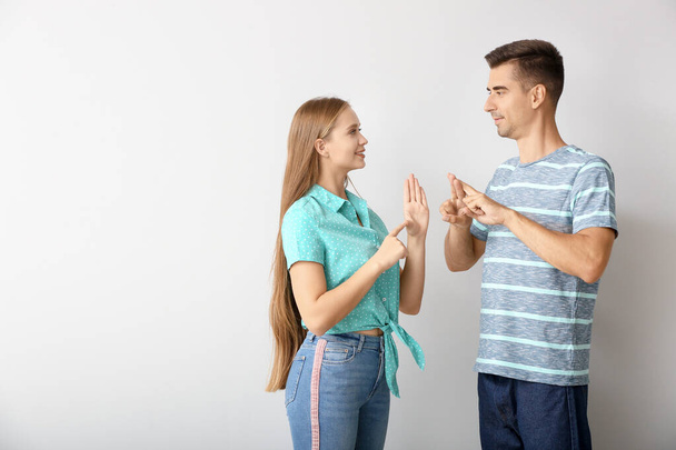 Jovem casal surdo mudo usando linguagem de sinais no fundo branco
 - Foto, Imagem