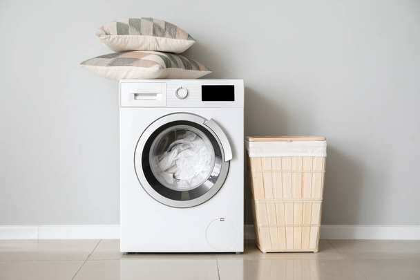 Сучасна пральна машина з пранням біля білої стіни
 - Фото, зображення
