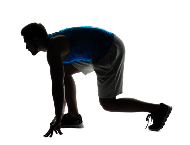 Silhouette sportos fiatalember crouch start pozícióban fehér háttér - Fotó, kép