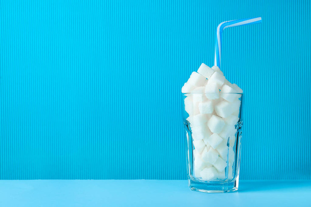 Glass with sugar cubes and straw on color background - Photo, Image