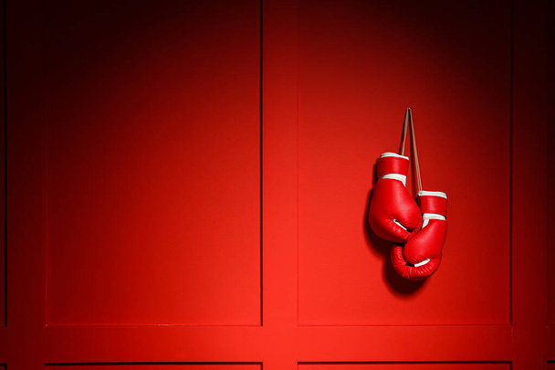 Pair of boxing gloves hanging on color wall - Photo, Image