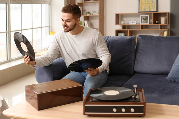Young man listening to music through record player at home - Photo, Image
