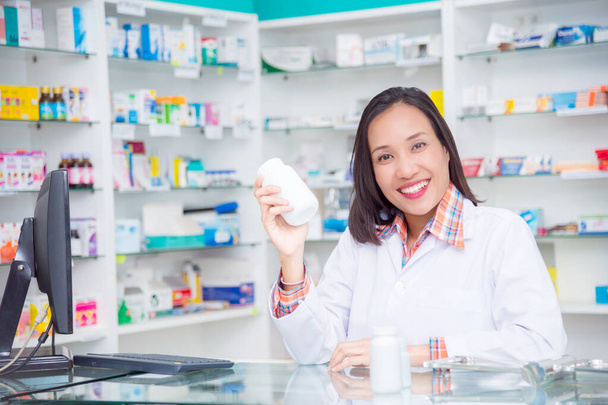 Όμορφη ασιατική φαρμακοποιός στέκεται στο φαρμακείο και χαμογελά  - Φωτογραφία, εικόνα