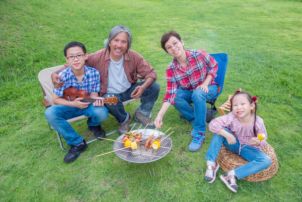 アジアの家族のグループは、ストーブの上でバーベキューや甘いトウモロコシを焼く  - 写真・画像