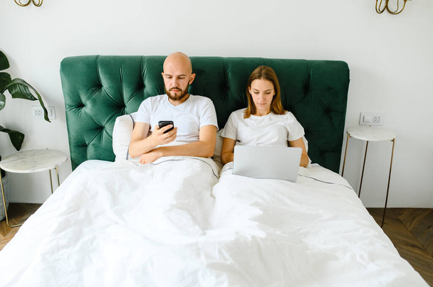 young couple using laptop together in bed  - Foto, afbeelding