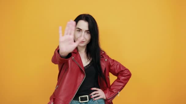 Mujer joven seria mostrando gesto de stop con palma aislada en la pared amarilla
 - Metraje, vídeo