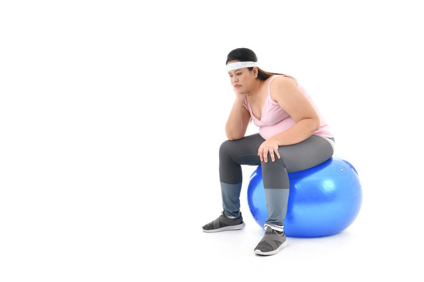 otyła Azji kobieta siedzi na siłowni piłka wygląda znudzony odizolowany na białym tle - Zdjęcie, obraz